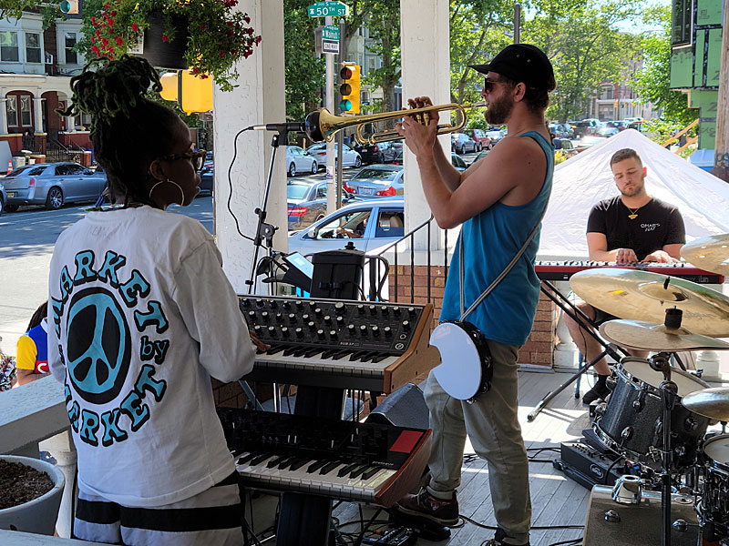 From left, Kayla Childs, Eric Sherman and Max Hoenig of Omar's Hat on the porch during Porchfest 2022 at the Paul Robeson House & Museum, June 4, 2022.