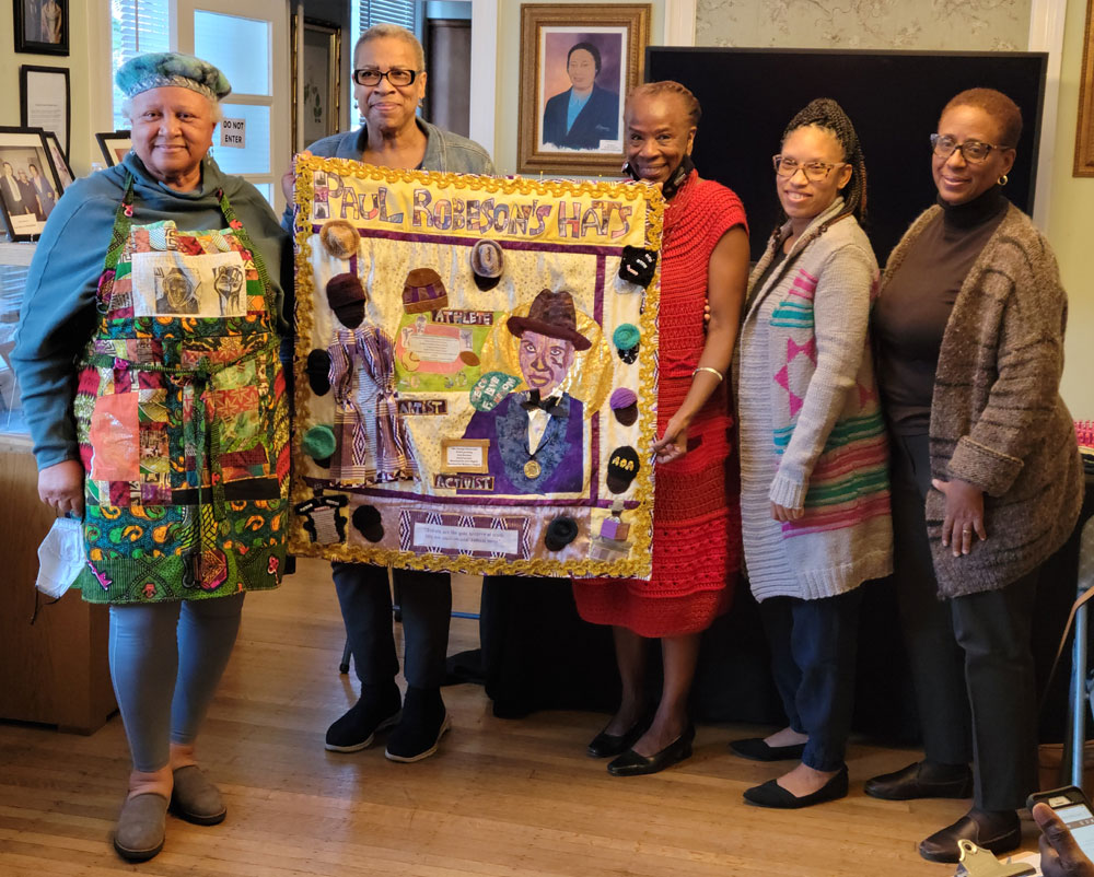 Members of Sisters Interacting Through Stitches with the "Paul Robeson's Hats" quilt they made for the Paul Robeson House & Museum. They mad a presentation at the house on Oct. 9, 2022. 