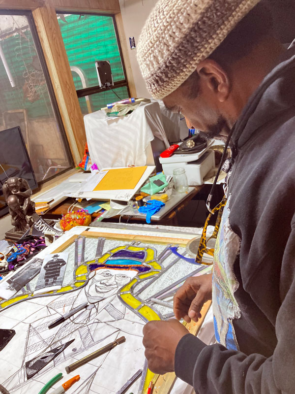 Artist Ramsess of Los Angeles works on the border of the stained-glass window for the front door of the Paul Robeson House & Museum. Photo by Asake-Denise Jones.